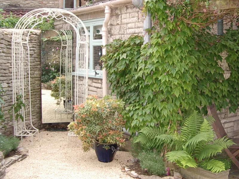 The Italian Courtyard Garden — After The same space but transformed with Mediterranean-inpsired planting, archways and mirrors