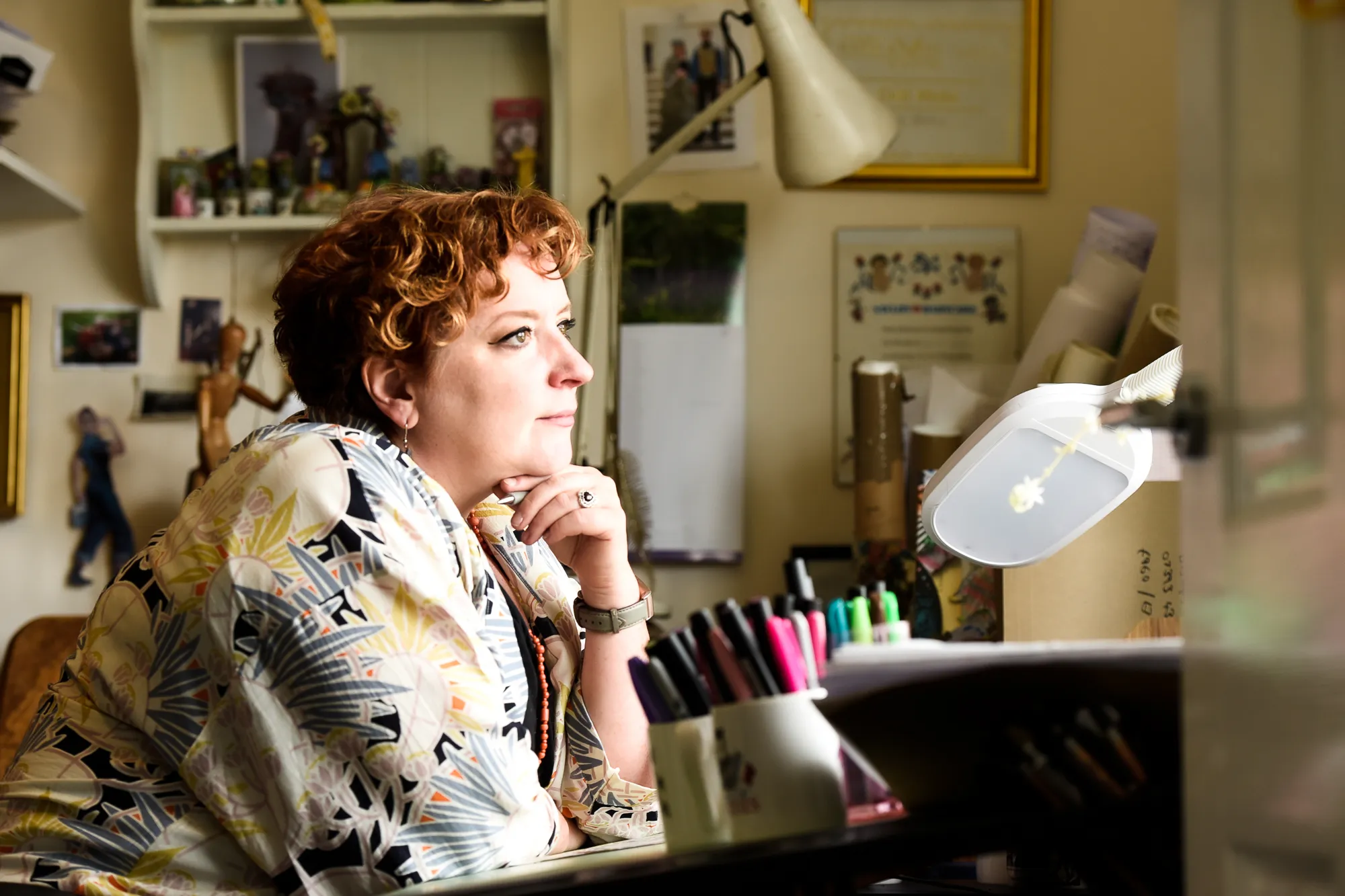 Charlotte sitting at a drawing board and looking out of the window. Photo by Victoria Tapper