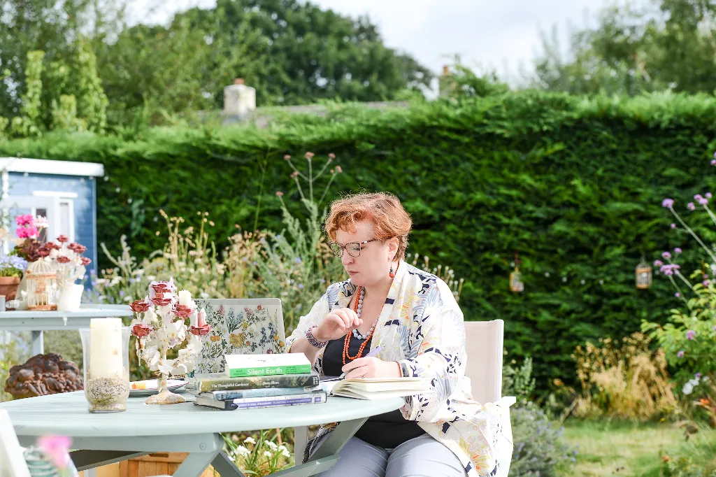 Charlotte sits in the sun at a table in her garden, reading several books. Photo by Victoria Tapper