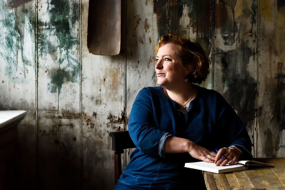 Charlotte taking notes at a table in a shed. Photo by Victoria Tapper