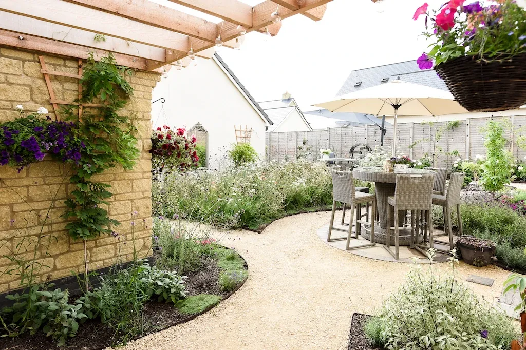 The finished garden with a table and chairs on gravel paths winding through shrubs and wildflowers. Photo by Victoria Tapper